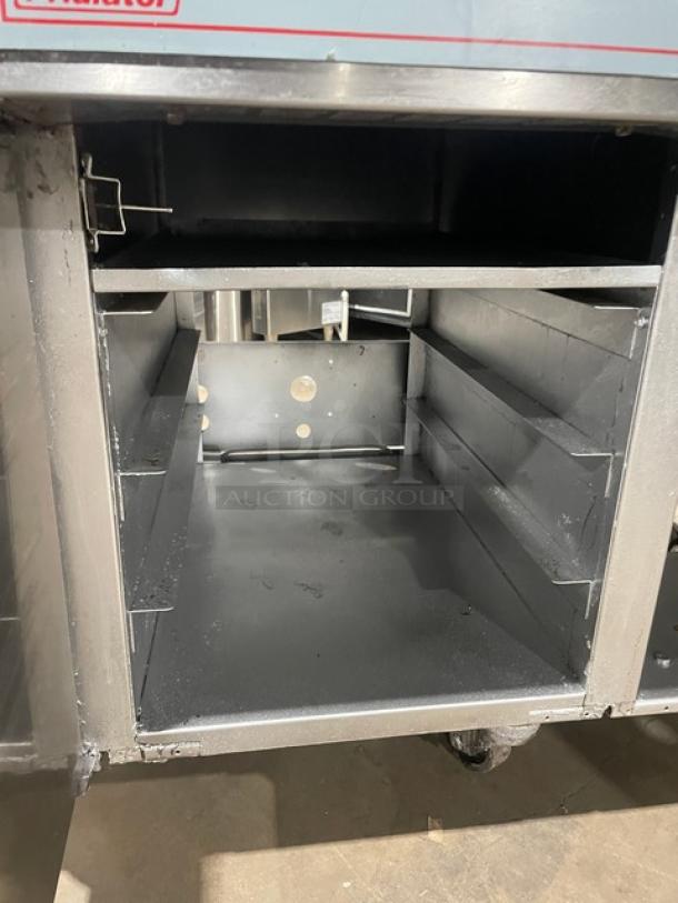 Pitco Frialator commercial 2-bay deep fat fryer system, stainless steel, with center enclosed pan cabinet, splashback, and basket hanger, on casters.