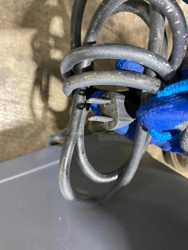 Coiled power cord of Hobart Steakmaster Meat Tenderizer. Plug shown; item is 115V, 1 Phase. Blue glove holds cord.