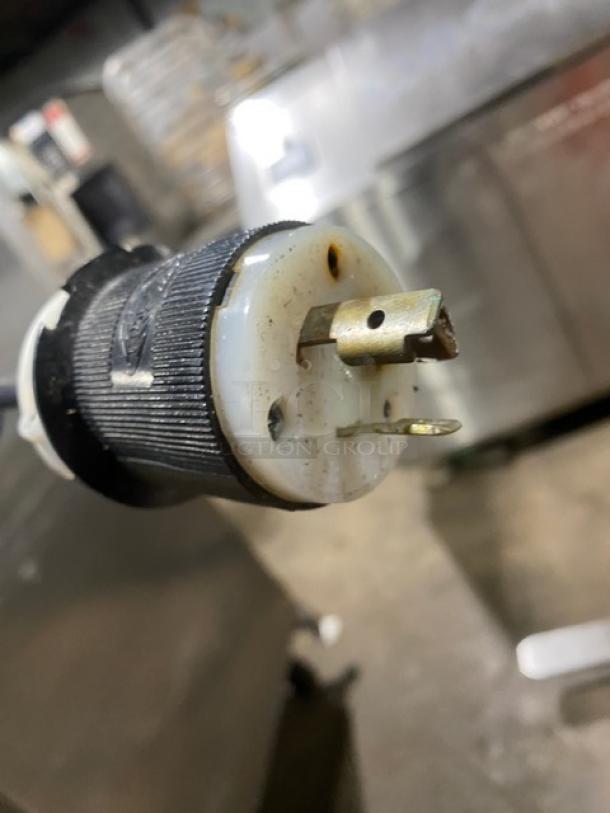 Close-up of the plug for a Traulsen RET132EUT-FHS refrigerator, showing three prongs and a black grip, indicating 115V compatibility.