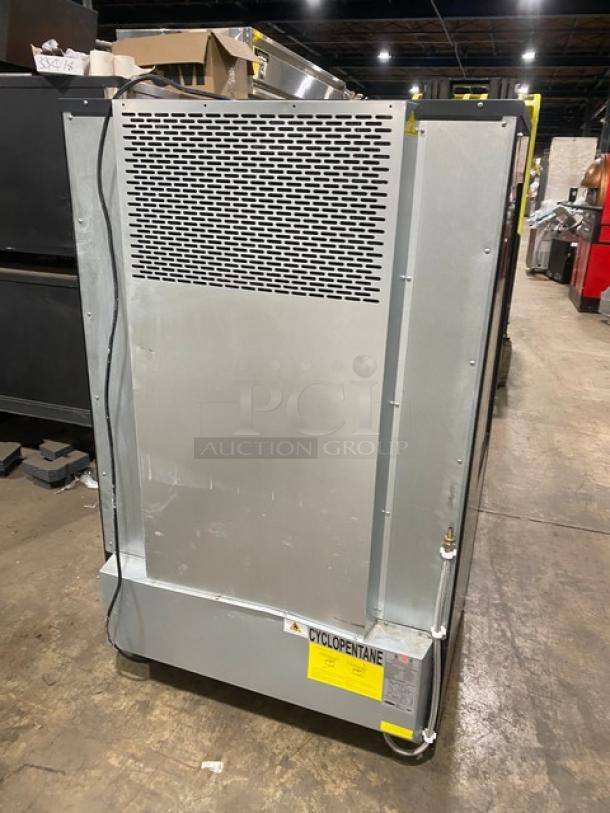 Kool-It KOM-36XBK black refrigerated display case with adjustable shelving, powered by 110-120V, on legs, SN: 1203922050025.