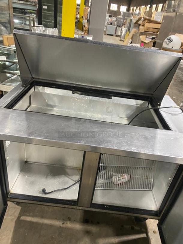 True TSSU-48-18M-B stainless steel 2-door refrigerated prep table, bain-marie style, with rack, on casters, open lid.