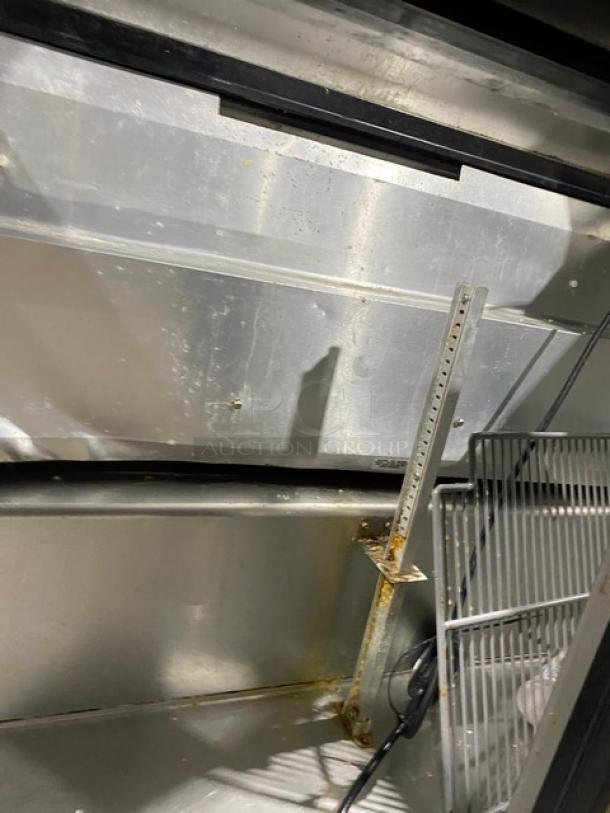 True TSSU-48-18M-B stainless steel 2-door refrigerated prep table interior, showing poly coated wired rack and metal frame.