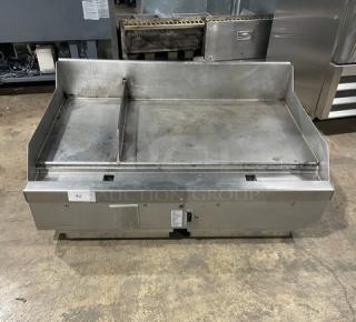 WoodStone stainless steel gas countertop split-top plancha griddle with back and side splash, on legs. Visible label indicates model details.