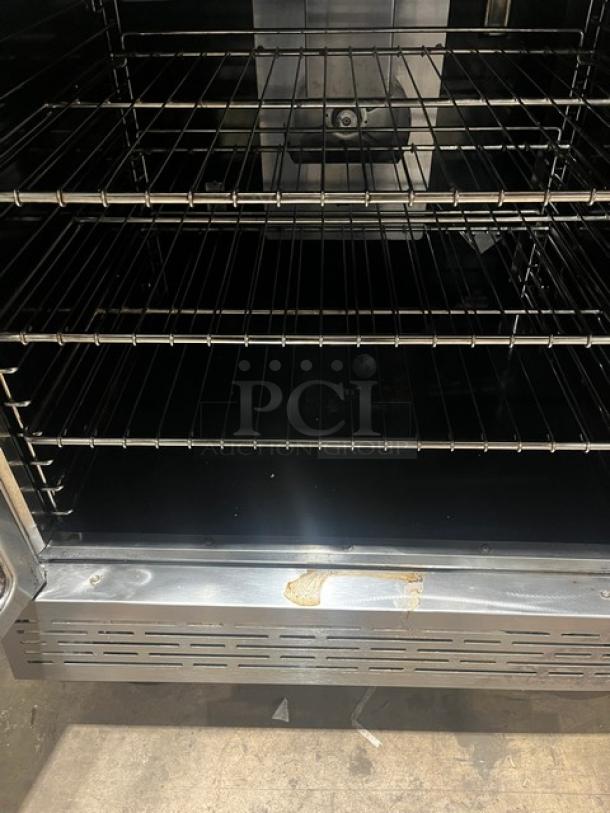 Imperial stainless steel double stacked convection oven, natural gas-powered. Includes wired oven racks, on casters. Visible wear on bottom trim.