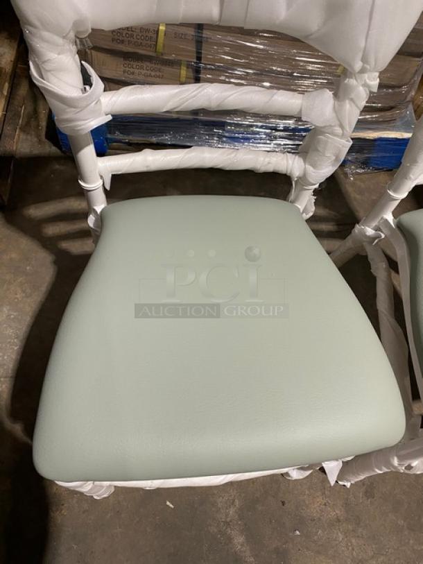 Brand new commercial white resin Chiavari dining chair with sage green cushion, in pristine condition, still wrapped.