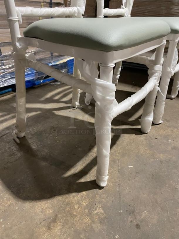 Brand new commercial white resin Chiavari dining chair with sage green cushion, wrapped for protection.