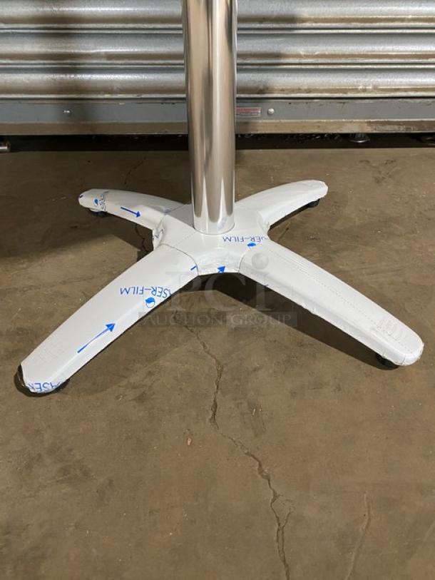 Brand new commercial rustic wooden dining table base, 4-leg pedestal style, shown with protective film on floor.