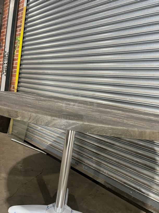 Brand new DuroWood 42" round dining table, model DW42, with a modern 4-way pedestal base, shown in warehouse setting.