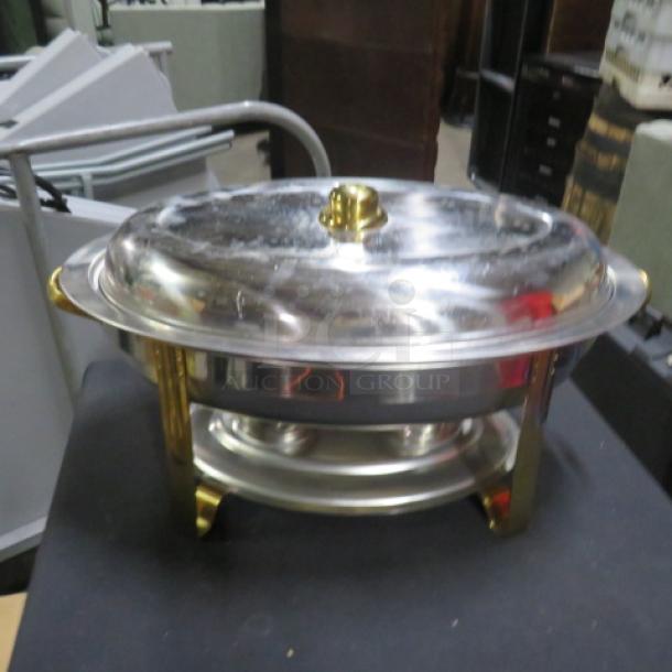 Oval stainless steel chafer with gold accents, good condition, includes lid and sturdy base. Ideal for catering events.