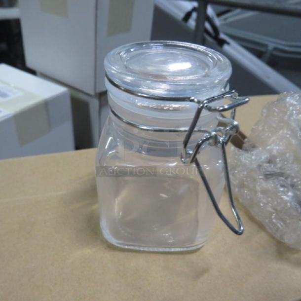 New mini glass spice jar with hinged lid, clear glass, metal clasp, model 6XBID, in pristine condition.