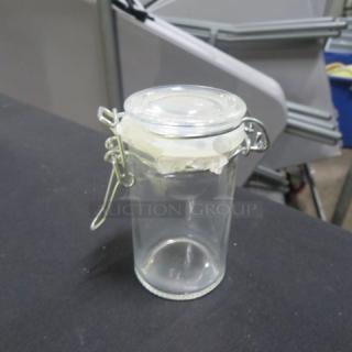 New mini glass spice jar with a hinged lid, model 6XBID. Clear glass, airtight metal clasp. Excellent condition.