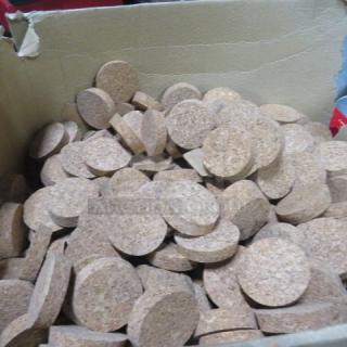 A box filled with new 2-inch cork lids, round, uniform size, clean and unused, suitable for jars or containers.