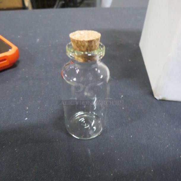 Set of 36 new glass bottles with cork lids, ideal for wedding favors. Each bottle is clear and unused.