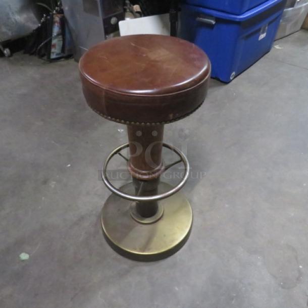 Metal and wooden barstool with brown leather cushioned seat, nail head trim, and footrest, in good condition.