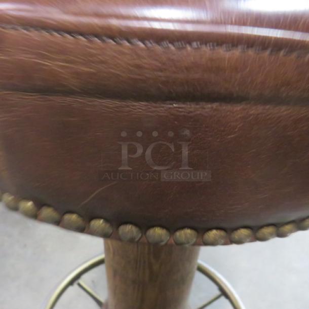 Brown leather cushioned barstool with nail head trim, metal footrest, and wooden base. Excellent condition.