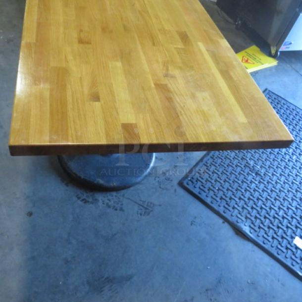 Solid wooden butcher block table with pedestal base, 48x30x30 inches. Features a polished, durable wood surface. Good condition.