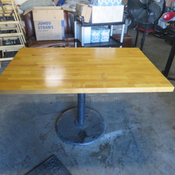 Solid wooden butcher block table on pedestal base, 48x30x30 inches. Smooth surface, good condition.