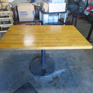 Solid wooden butcher block table on pedestal base, 48x30x30 inches. Smooth surface, good condition.