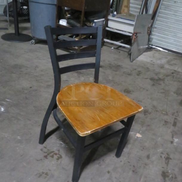 Black metal chair with a wooden seat, model 2XBID. Features a ladder-back design. Good condition.