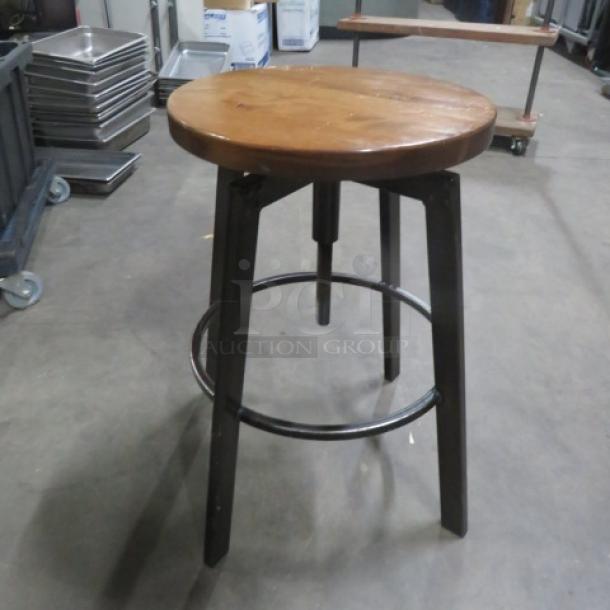 Black metal and wooden adjustable bar stool, round wooden seat, sturdy metal legs, footrest ring, good condition.