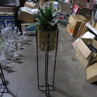 Metal planter with plant on tall black stand, good condition. Modern design, ideal for indoor decor. No visible tags.