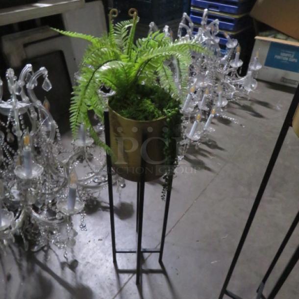Metal planter with lush green plant on tall stand. Features a metal pot and cascading foliage. Excellent condition.