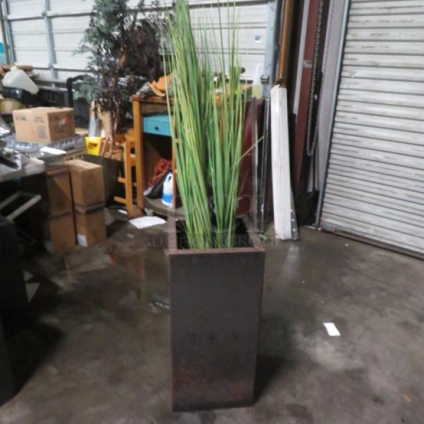 Tall square metal planter with decorative grass. Measures 14x14x29 inches. Slightly weathered condition.