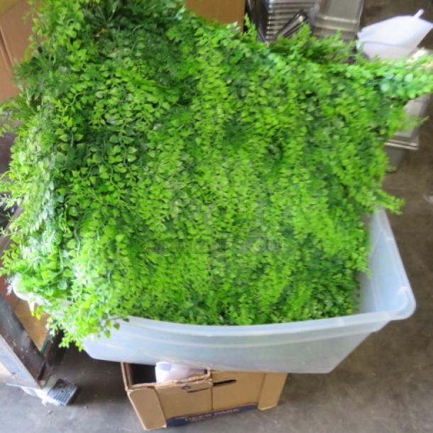 Large lot of artificial greenery in a plastic bin; vibrant green leaves, ideal for decorations or displays.