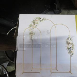 Three decorative gold metal arches, 5ft, 6ft, and 7ft, with floral accents, in good condition for event decor.