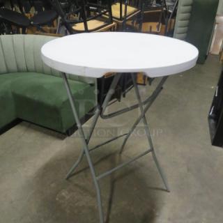 Cosco round bar height folding table, 31x43 inches, white top, metal legs, used condition, ideal for events or gatherings.