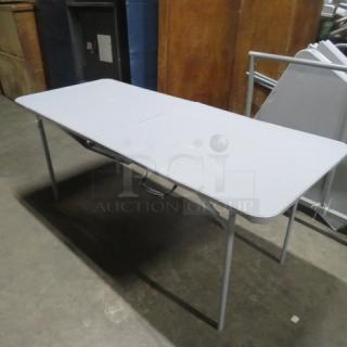 Cosco folding table, 72x29x30 inches, gray, durable construction, with central folding seam and grip handle for portability.