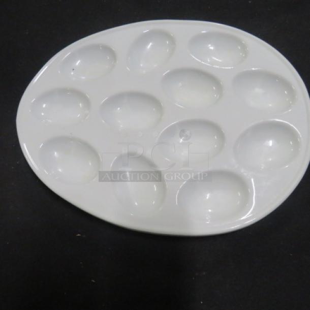 White ceramic egg platter with 11.5x9 dimensions, featuring 12 egg-shaped compartments, in good condition. No visible markings.