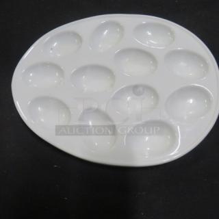 White ceramic egg platter with 11.5x9 dimensions, featuring 12 egg-shaped compartments, in good condition. No visible markings.