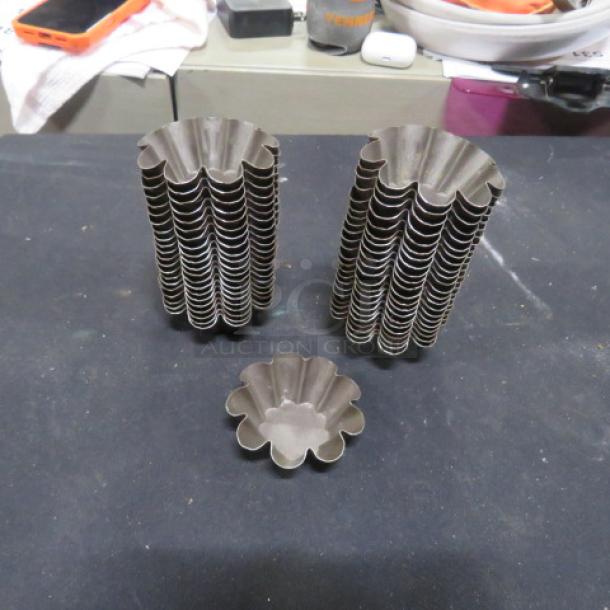 One lot of 44 mini tin molds, fluted design, used for baking. Stack shows neat organization. Good condition.
