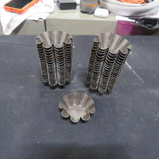 One lot of 44 mini tin molds, fluted design, used for baking. Stack shows neat organization. Good condition.