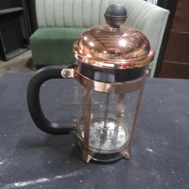 French coffee press, new, copper finish, glass carafe, black handle, plunger mechanism, elegant design, excellent condition.