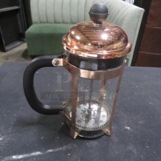 A new French coffee press with a copper finish, glass carafe, and black handle, in excellent condition.