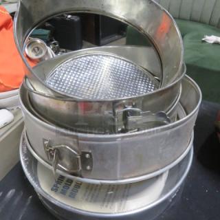Assorted springform pans, various sizes, metal with latching mechanisms, used condition.