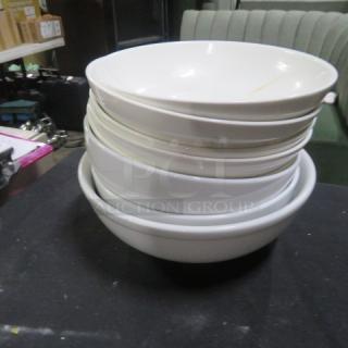 Stack of assorted white bowls, varying sizes, smooth finish, minor wear. Perfect for kitchen use or collection.