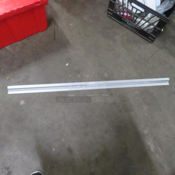 48-inch silver ticket rail, metallic finish, lying on concrete floor, no visible markings or labels.