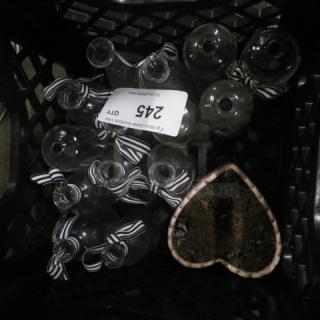 Assorted glass bottles with striped ribbons in a crate, includes a heart-shaped planter with soil. Label reads "245."