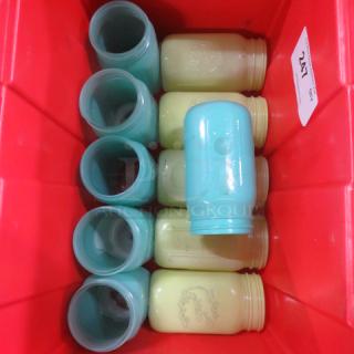 Lot of vintage mason jars in aqua and cream colors, stored in a red container. Some jars feature embossed patterns. Auction tag marked "247" visible.