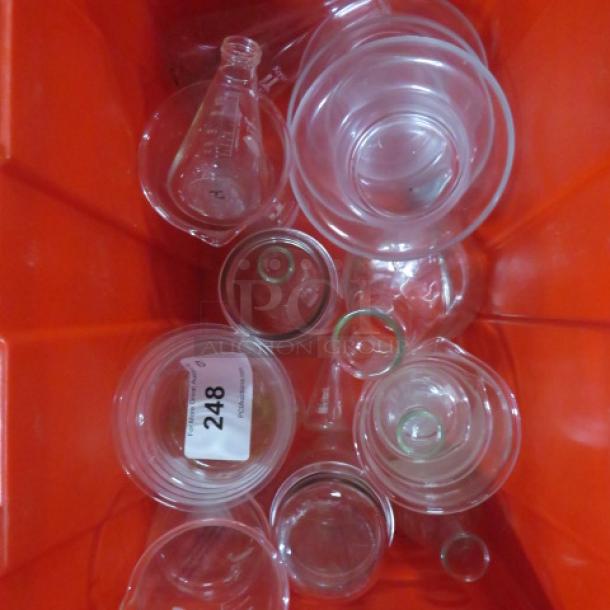 Set of assorted glassware in a red bin, including beakers and flasks. Visible tag marked "248." Items appear in good condition.