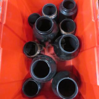 A lot of black ceramic candle holders in a red container, varied sizes, some with decorative rims, in good condition.