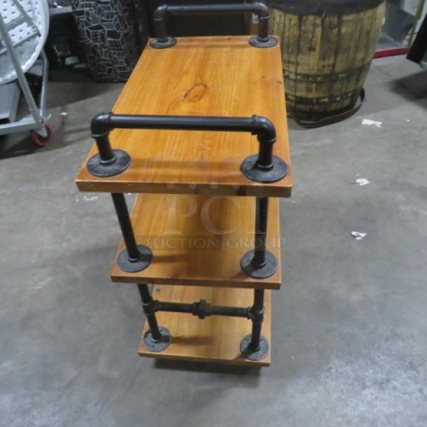 Industrial-style wooden cart with three shelves on casters, 27.5x16x35 inches, featuring metal pipe handles, in good condition.