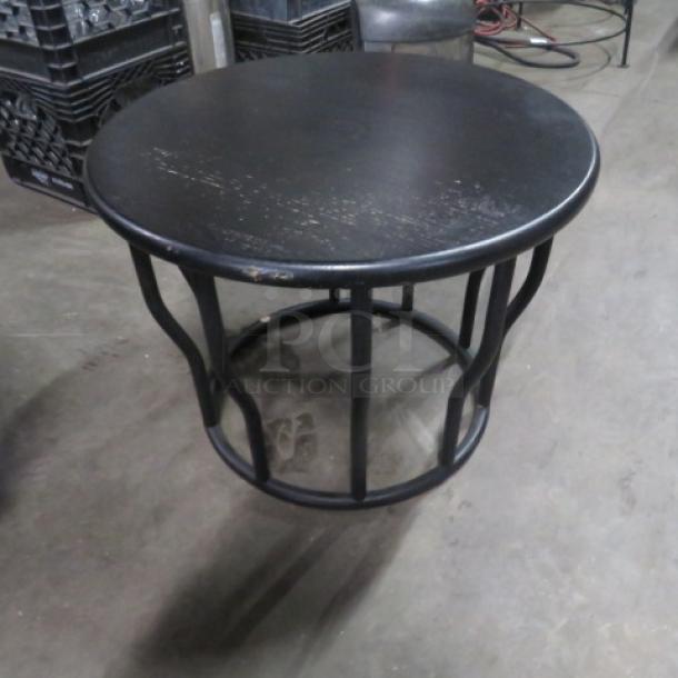 Round table with black metal top and wooden base, 21.5x16 inches. Slightly worn condition, sturdy design.