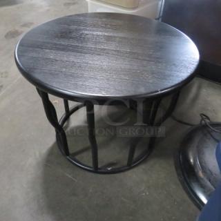Round table with black metal top, wooden base, measuring 21.5x16 inches. Solid construction, modern design.