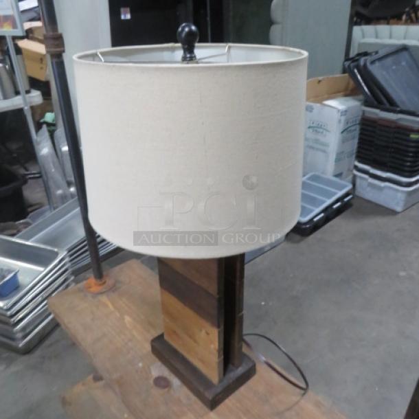 Wooden lamp with beige fabric shade, two-tone wood base, modern design, used condition, visible power cord.