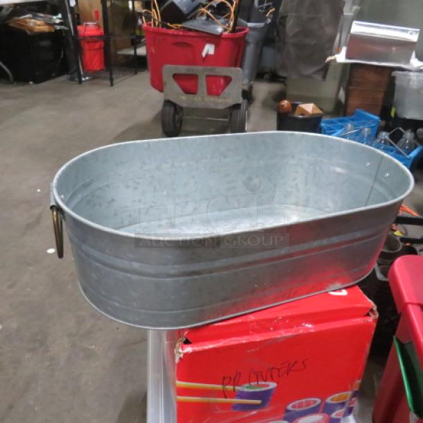Galvanized metal beverage tub, oval shape, sturdy construction, with handles, good condition, suitable for parties or events.