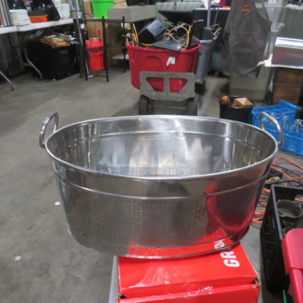 Stainless steel beverage tub with dual handles, polished finish, excellent condition, on display in a warehouse setting.